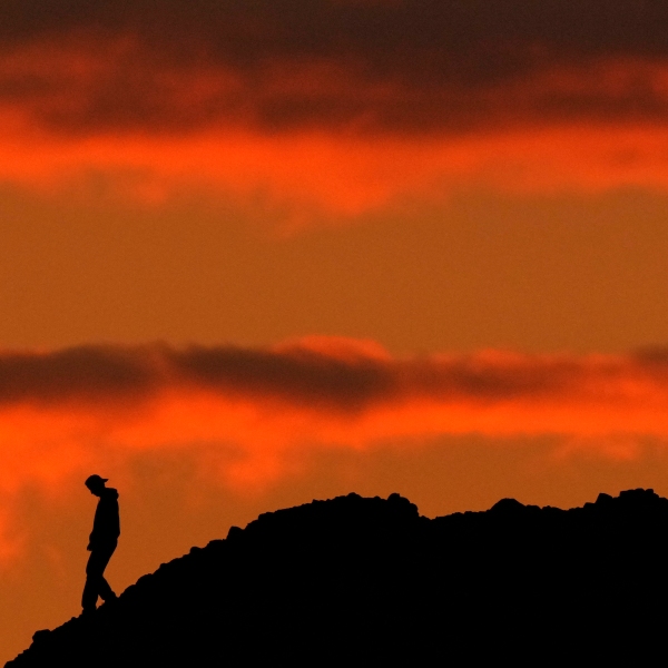 A person is silhouetted against the sky at sunset at Papago Park in Phoenix on Thursday, March 2, 2023. The homicide rate for older U.S. teenagers rose to its highest point in nearly 25 years during the COVID-19 pandemic, and the suicide rate for adults in their early 20s was the worst in more than 50 years, government researchers said Thursday, June 15. (AP Photo/Charlie Riedel)