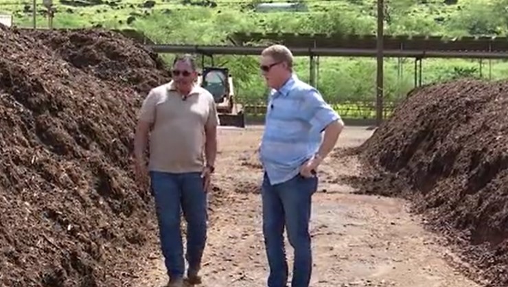 A photo shows David Souza (left) owner of Island Topsoil and KHON2 anchor Howard Deshefsky (right) as they inspect green waste being turned into topsoil on Wednesday, March 15, 2023 in Honolulu, Hawai'i.
